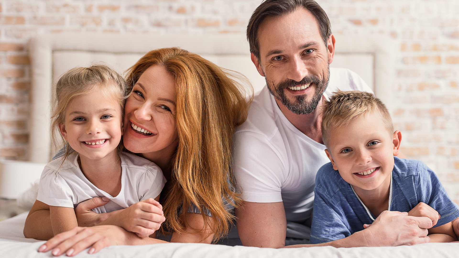 Vierköpfige Familie mit zwei Kindern, lachend auf Sofa